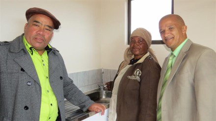 Mev. Hilda Jack draai vir die eerste keer die kraan in haar nuwe tuiste oop. By haar is links,rdl. Henry Jones en  rdl. Daniel Maritz, Uitvoerender Onderburgemeester van George.